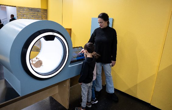 Une adulte et deux petits enfants jouent avec la machine d'imagerie au Carrefour de la santé d'ActivIdée au Centre Harbourfront.