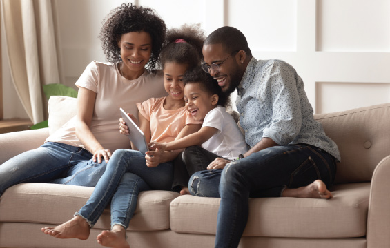 Deux parents et deux enfants jouent aux devinettes sur leur tablette.