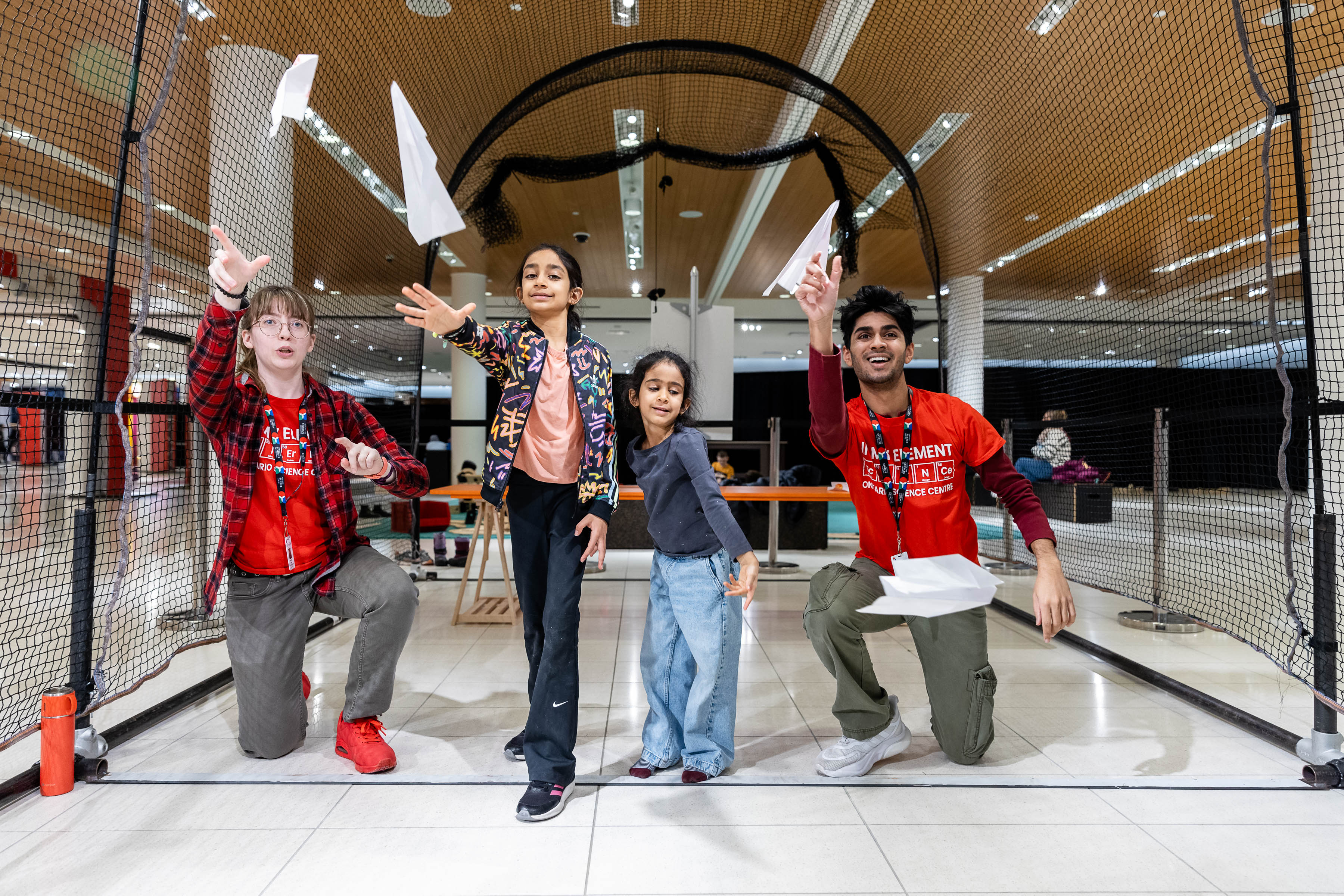 Deux enfants lancent des avions en papier avec deux membres de l'équipe du Centre des sciences à CF Sherway Gardens.