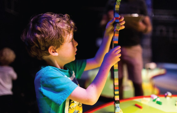 Un enfant empile des blocs Lego pour faire une grande tour.