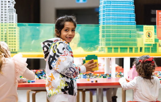 Un enfant montre fièrement sa création Lego lors de l'exposition Les tours de demain.