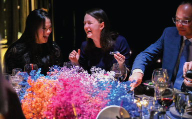 Trois convives rient et mangent à table.