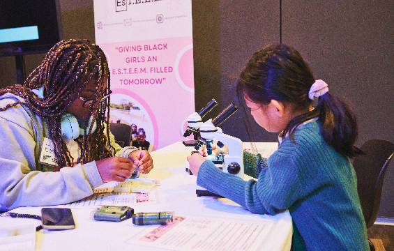 Deux filles mènent une expérience scientifique au microscope pendant un programme de Black ESTEEM.